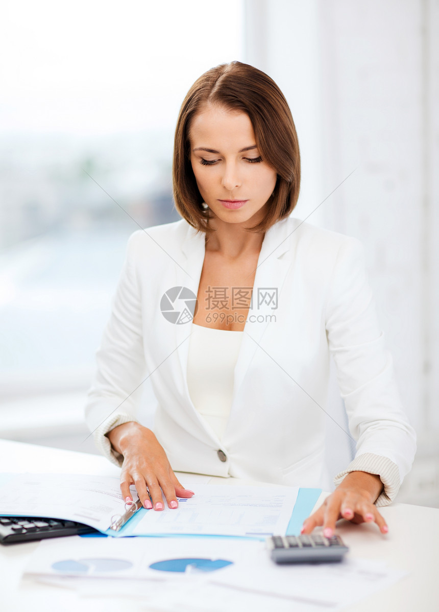 商业女商人办公室里用计算器工作图片