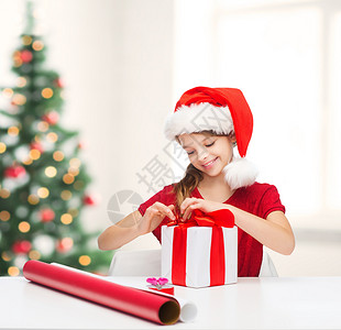 诞节,冬天,幸福的微笑的女孩戴着诞老人的帽子,带着礼品盒包装纸图片