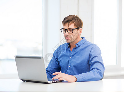 技术,商业生活方式的戴眼镜的男人家用笔记本电脑工作图片