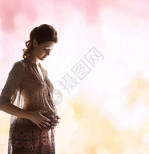 家庭,母亲怀孕的剪影背光图片怀孕美丽的女人触摸她的肚子图片