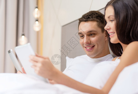 酒店,旅游,人际关系,技术,人际关系幸福的微笑的夫妇床上与平板电脑图片
