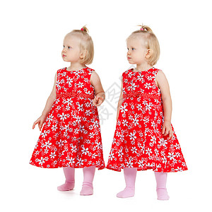 孩子双胞胎的两个相同的双胞胎女孩穿着红色的衣服,看着某个地方背景图片