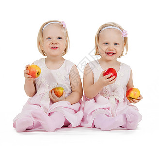 孩子,食物双胞胎的两个相同的双胞胎女孩玩苹果背景图片