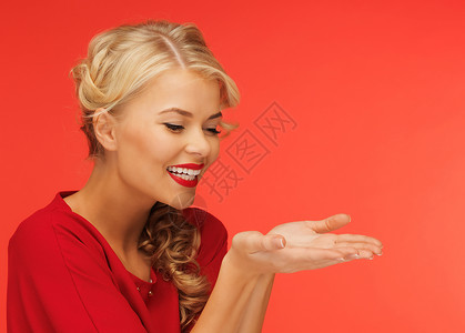 穿着红色连衣裙的可爱女人她的手掌上展示了些东西图片