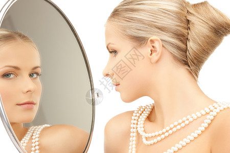 女人戴着珍珠项链,看着镜子高清图片