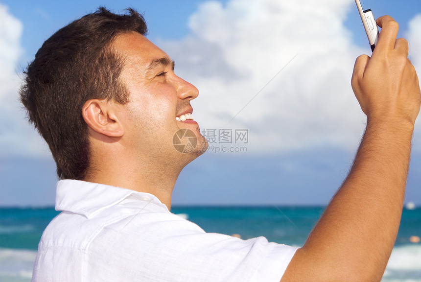 海滩上玩手机的快乐男人图片