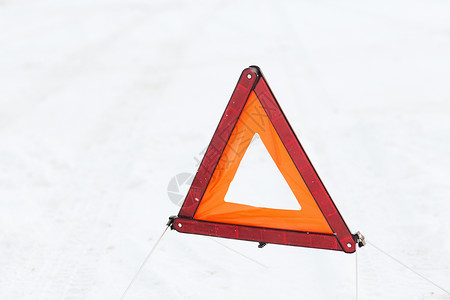 发信号运输冬季雪上警告三角形的特写背景