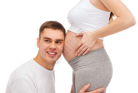 怀孕,父母幸福的快乐的父亲听他怀孕的妻子的肚子图片