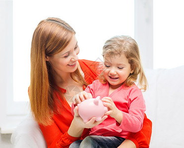 家庭,孩子,金钱,投资家快乐的人的快乐的母亲女儿与小粉红色储蓄罐图片