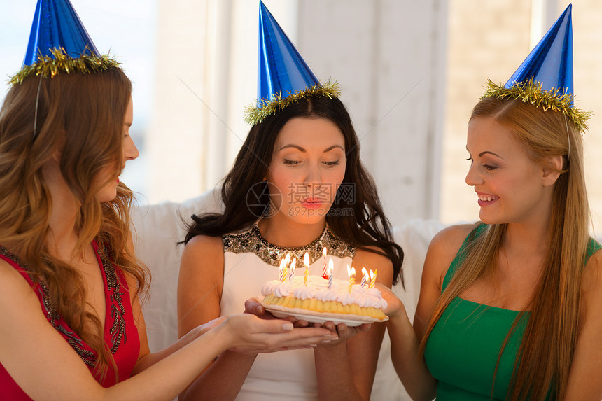 庆祝,食物,朋友,单身派,生日三个微笑的女人戴着蓝色的帽子,着蜡烛蛋糕图片