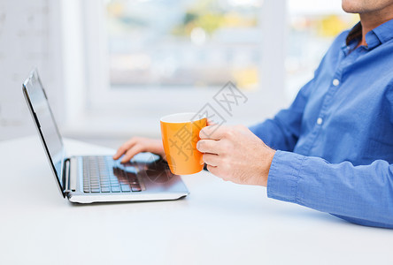 技术,饮料生活方式的男手杯热茶咖啡与笔记本电脑图片