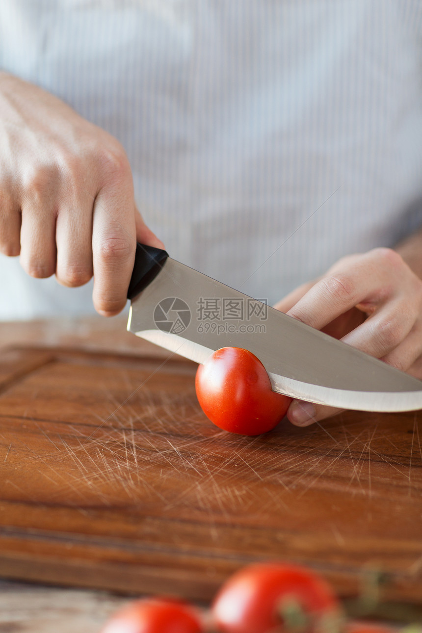 烹饪家庭用锋利的刀砧板上用男手切西红柿图片
