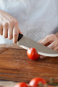 烹饪家庭用锋利的刀砧板上用男手切西红柿图片