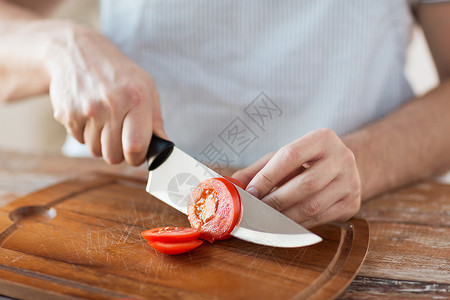 烹饪家庭用锋利的刀砧板上用男手切西红柿高清图片