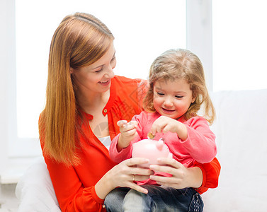 家庭,孩子,金钱,投资家快乐的人的快乐的母亲女儿与小粉红色储蓄罐图片