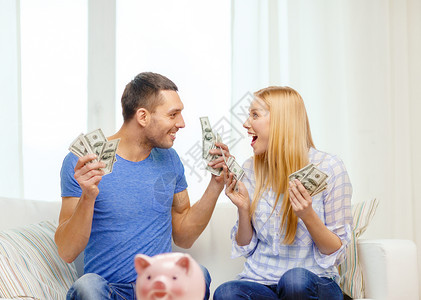 爱,家庭,金融,金钱幸福微笑的夫妇与金钱储蓄罐家里的桌子图片