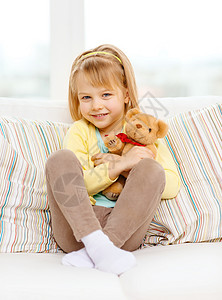孩子,玩具幸福微笑的小女孩泰迪熊坐家里的沙发上图片