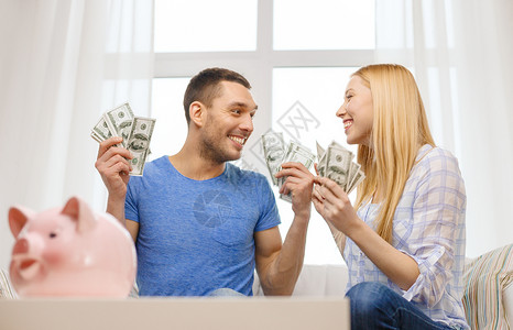 爱,家庭,金融,金钱幸福微笑的夫妇与金钱储蓄罐家里的桌子图片