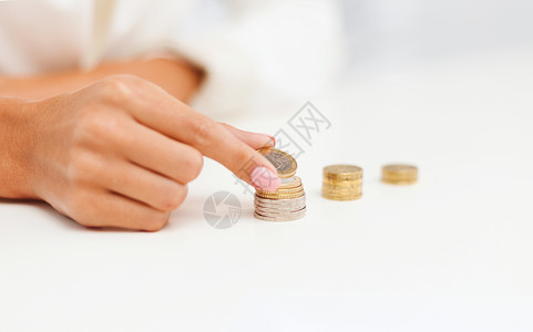 商业省钱的女手把欧元硬币放入办公室的专栏图片