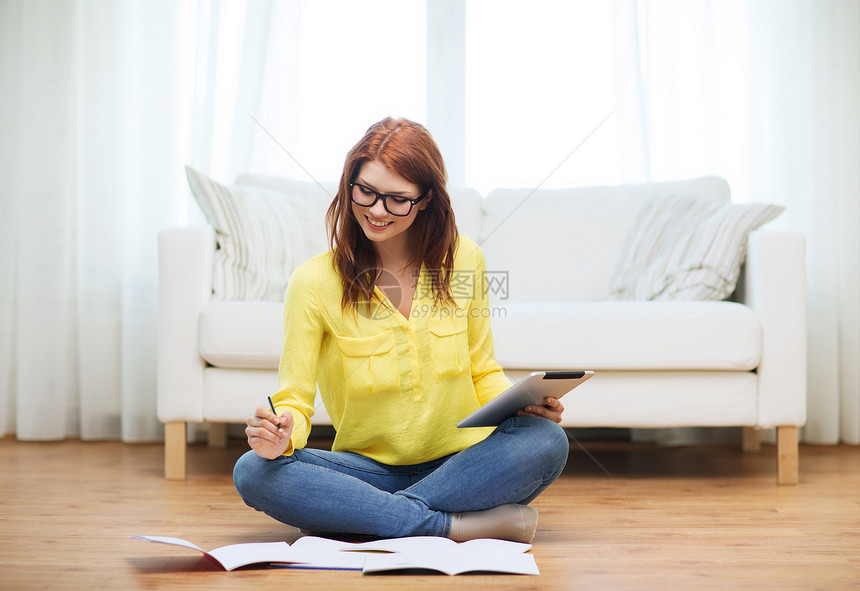 商业教育技术微笑的女学生戴眼镜,家里笔记本平板电脑图片