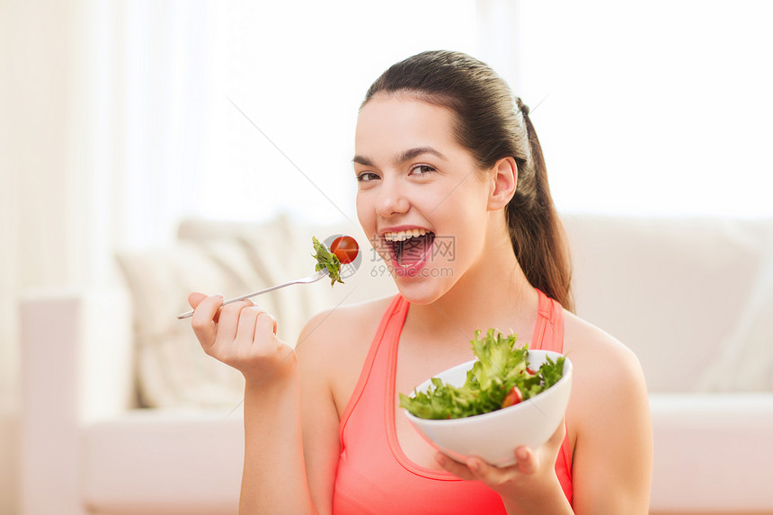 健康,节食,家庭幸福的微笑的运动少女与绿色沙拉家里图片