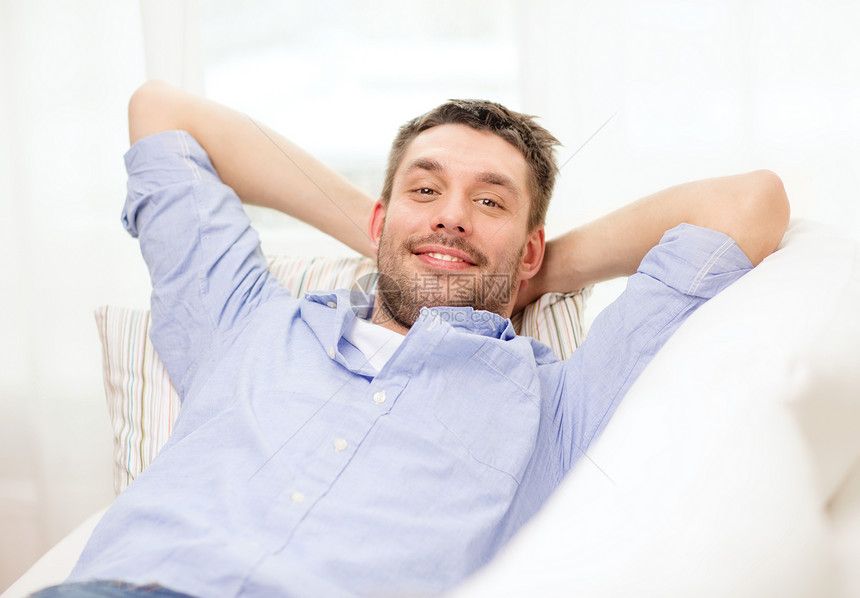 家庭幸福的微笑的男人躺家里的沙发上图片