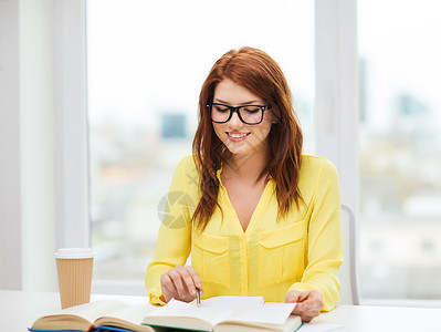 教育理念微笑的学生女孩戴眼镜读书,图书馆笔记背景图片