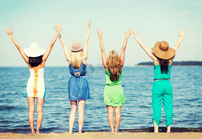 暑假假期女孩们海滩上举手图片