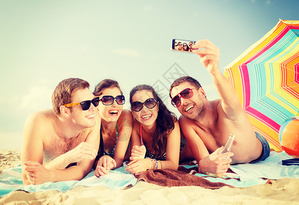微笑的人在海滩上用智能手机拍照高清图片