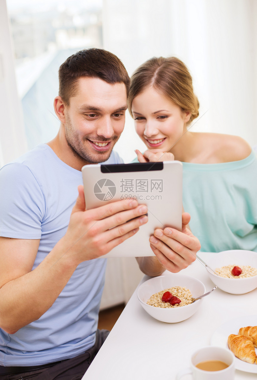 食物,家庭,夫妇技术微笑夫妇与平板电脑阅读新闻拍照,并家里吃早餐图片