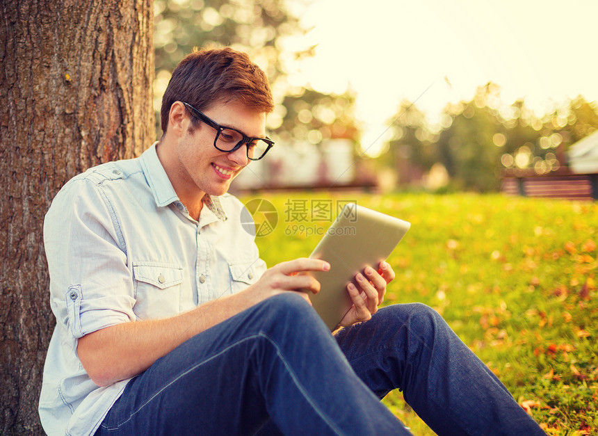 教育技术互联网微笑的男学生戴眼镜,外平板电脑图片