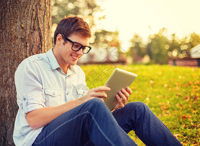 教育技术互联网微笑的男学生戴眼镜,外平板电脑图片