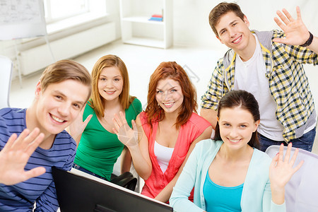 微笑的学生在学校的计算机课上挥手图片