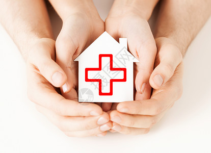 交叉的手医疗保健医药慈善理念男女手着带红十字标志的白纸屋背景