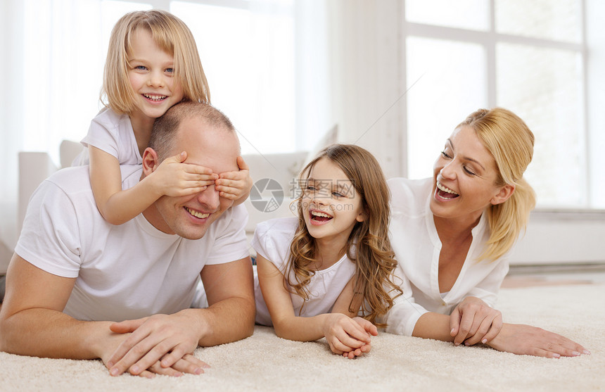 微笑的家庭两个小女孩躺家里的地板上,玩得开心图片