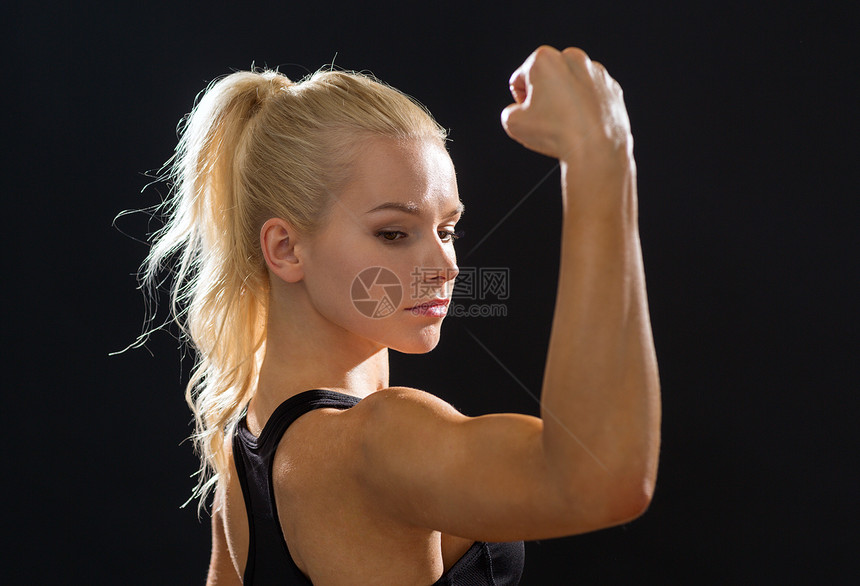 健身饮食接近美丽的运动妇女弯曲她的头肌图片