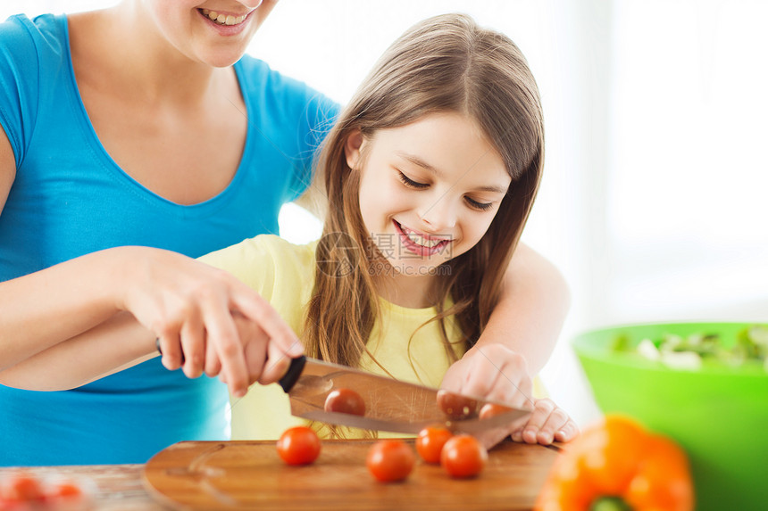 家庭,孩子,烹饪家庭微笑的小女孩母亲厨房切西红柿图片