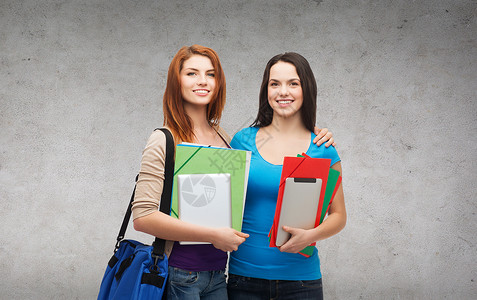 教育,技术人的两个微笑的学生与袋子,文件夹平板电脑站立图片