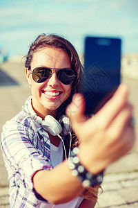 假期旅游微笑的十几岁女孩户外用智能手机相机拍照图片