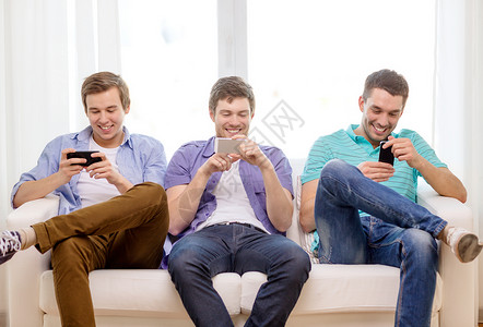 友谊,技术家庭微笑的男朋友与智能手机家里高清图片