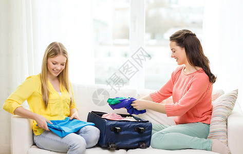 旅行,假期友谊的两个微笑的十几岁女孩家里打包手提箱图片