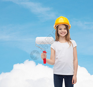 建筑人的微笑的小女孩防护头盔与油漆滚筒图片