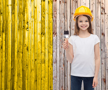 建筑人的微笑的小女孩防护头盔与油漆刷图片