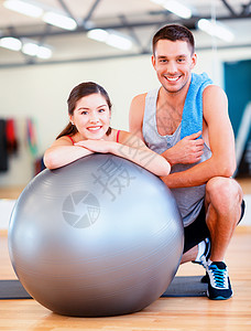 健身,运动,训练,健身房生活方式的两个微笑的人与健身球健身房图片