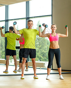 运动,健身,生活方式人们的微笑的男人女人戴着哑铃健身房锻炼图片