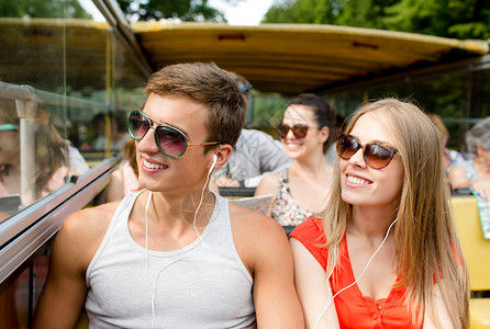 友谊,旅行,假期,夏天人们的微笑夫妇与耳机旅游巴士图片