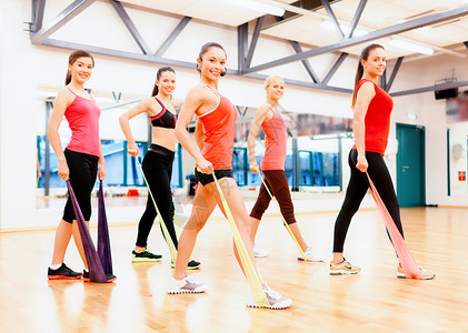 健身,运动,训练,健身房生活方式的群微笑的人与教练健身房里用橡皮筋锻炼图片
