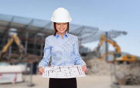 建筑,发展,建筑建筑微笑的女商人戴着白色头盔看蓝图图片