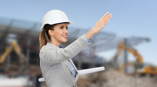 建筑,发展,建筑建筑微笑的女人戴着白色头盔与蓝图图片