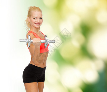 健身,保健运动轻的运动妇女与沉重的钢哑铃图片